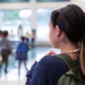 A middle school girl standing alone in a school cafeteria
