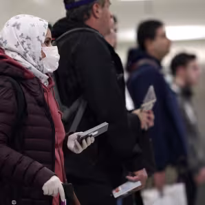 Travelers arrive at a U.S. airport wearing masks during the COVID-19 pandemic