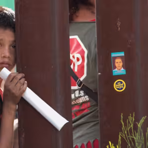 A boy peers through fencing at the U.S.-Mexico border. 