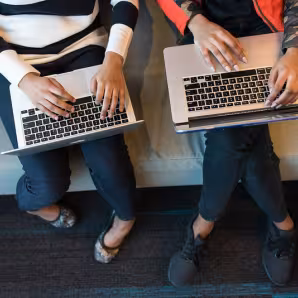 Two women use their laptops