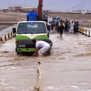 People pulling vehicles from a flooded road in an Afghan village