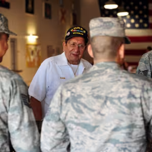 Two men in military attire stand with a veteran