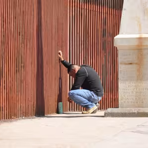 A man says goodbye to his partner through the border fence