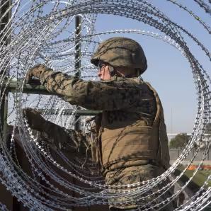 U.S. Marine secures barbed-wire fencing at the California-Mexico border.