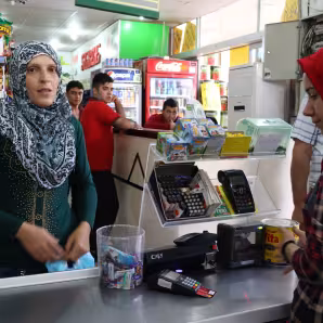 A Syrian refugee woman uses a special e-card to purchase food at a grocery store in Turkey. 