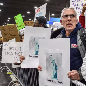 A man holds a sign protesting the travel ban at an airport