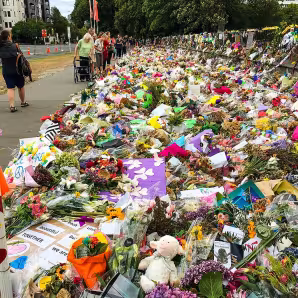 People pass by flowers laying on a street