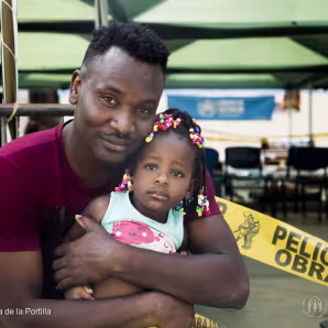 A Haitian man hugs his daughter in Peru.