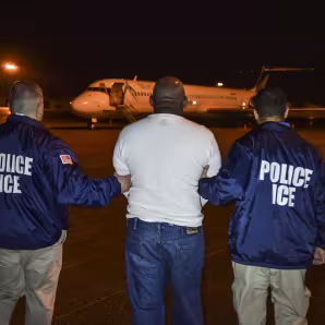 A migrant scheduled to be deported from the United States is escorted to a charter flight. 