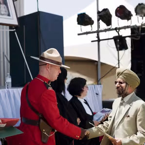 A new Canadian citizen greets a Royal Canadian Mounted Police officer at a citizenship ceremony