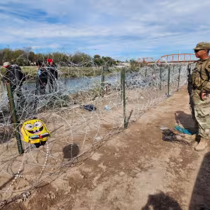 A member of the Texas National Guard faces migrants in Eagle Pass, Texas.