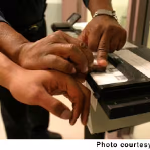 An officer in the Harris County (TX) Sheriff's Office takes the fingerprints of an individual it arrested. Harris County has a 287(g) agreement with ICE.