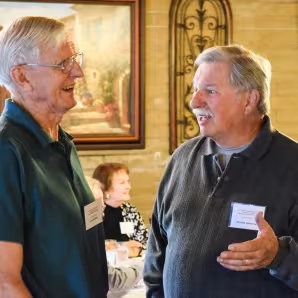 Two men talk during a retiree luncheon
