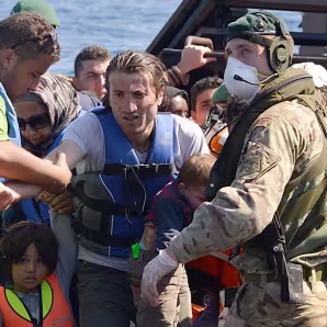 Sailors and marines on the HMS Bulwark help migrants ashore in Italy.