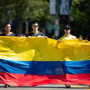 Varias personas portan una bandera gigante de Colombia en un desfile en Washington, DC.