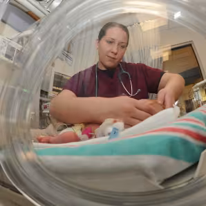 An intern examines a newborn baby in the Neonatal Intensive Care Unit.