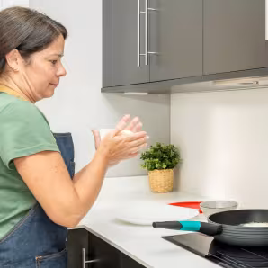 Una mujer prepara arepas en la cocina. 
