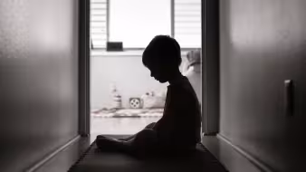 A silhouette of a young child looking sad and alone
