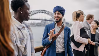 People of different ethnic backgrounds engage in a lively discussion, against the backdrop of Sydney Harbour Bridge