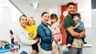 Three parents holding toddlers in a preschool classroom