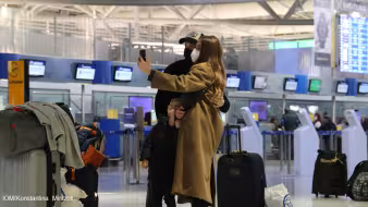 People wearing face masks take a selfie at an airport