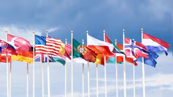 The flags of many different countries flying in the wind.