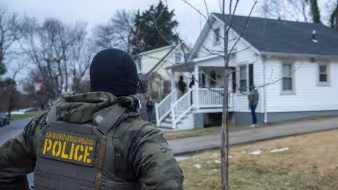An ICE officer outside a home in Baltimore, Maryland.