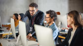 Image of teacher helping group of students at their computers