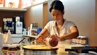 Image of female worker at the Boqueria market in Barcelona making a crepe