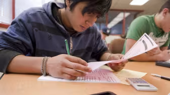 Student looking over a paper at a desk