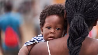A Haitian child looks over his mother's shoulder in Panama