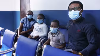 Two adults and two children wearing face masks at a migration health centre in Nigeria