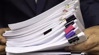 Worker holds stack of paperwork