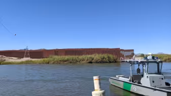 Image of U.S.-Mexico border wall and Border Patrol boat