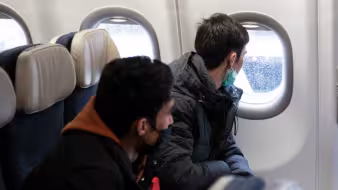 Two people on an airplane looking out the window