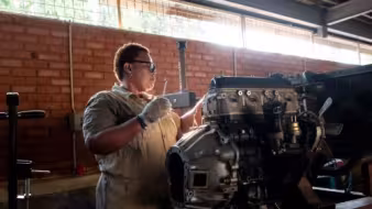 Migrant working on repairing or building an engine