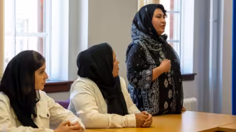 Afghan woman speaking to other afghan women at meeting table