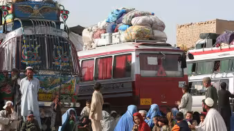 Returned Afghan refugees wait by the buses in Kabul that will take them back home.
