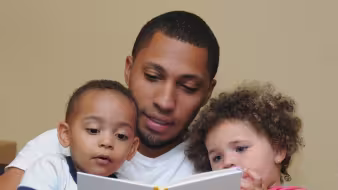 An immigrant father reading with his children.