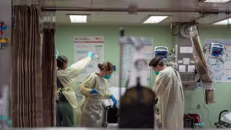 Three health professionals wearing masks in a hospital