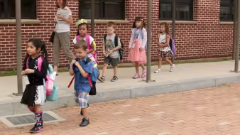Young students walking with their teacher.