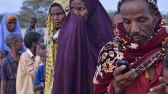 A refugee texts while waiting to register at Ifo refugee camp in Dadaab, Kenya.