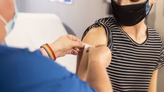 A health-care provider places a bandage on the injection site of a patient who just received a vaccine.