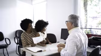 Mother and daughter sitting at a desk for an appointment