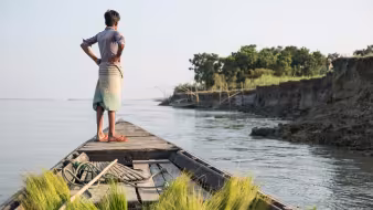 A boy on a boat in a Bangladeshi community affected by river erosion