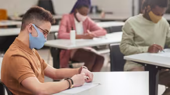 Side view portrait of young man and two other students taking a test