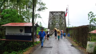 People walking across the bridge over the Sixaola River at the border between Panama and Costa Rica
