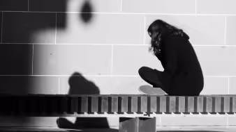Girl sitting on a bench facing a wall