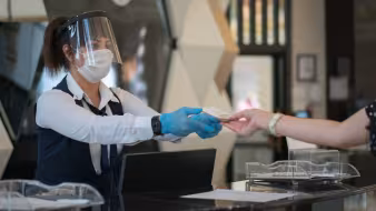 Receptionist wearing personal protective equipment while interacting with a customer