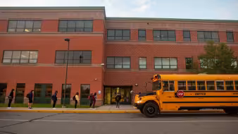 Students lined up outside their high school at the start of the school day.